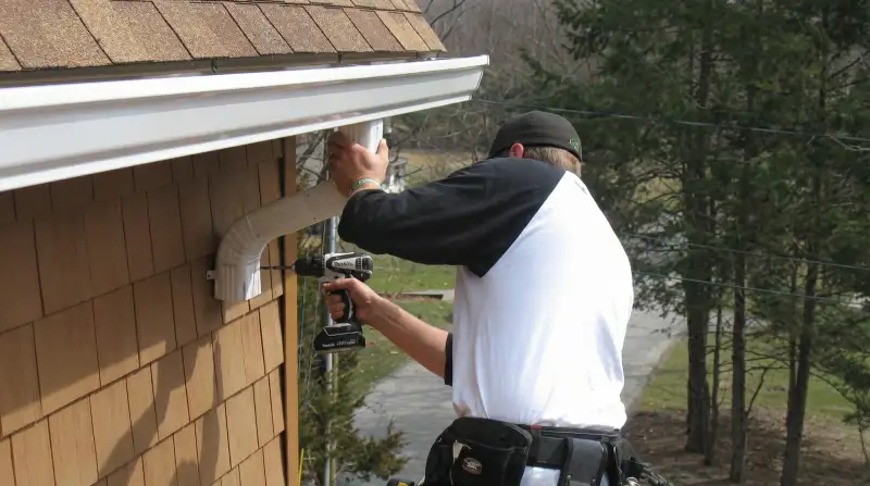 Professional contractor installing tan vinyl siding panels on a residential home exterior in Raleigh, NC